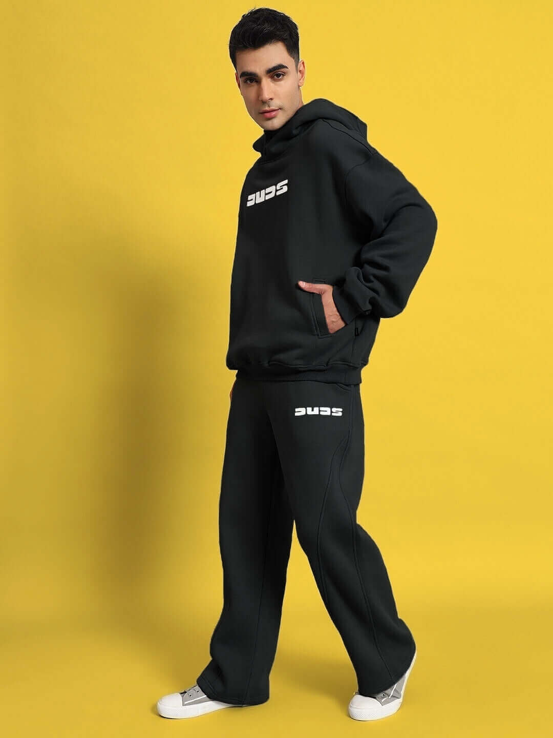 Model wearing WEARDUDS SHOOTER FLEECE CO-ORD BLACK hoodie and pants against a yellow background.