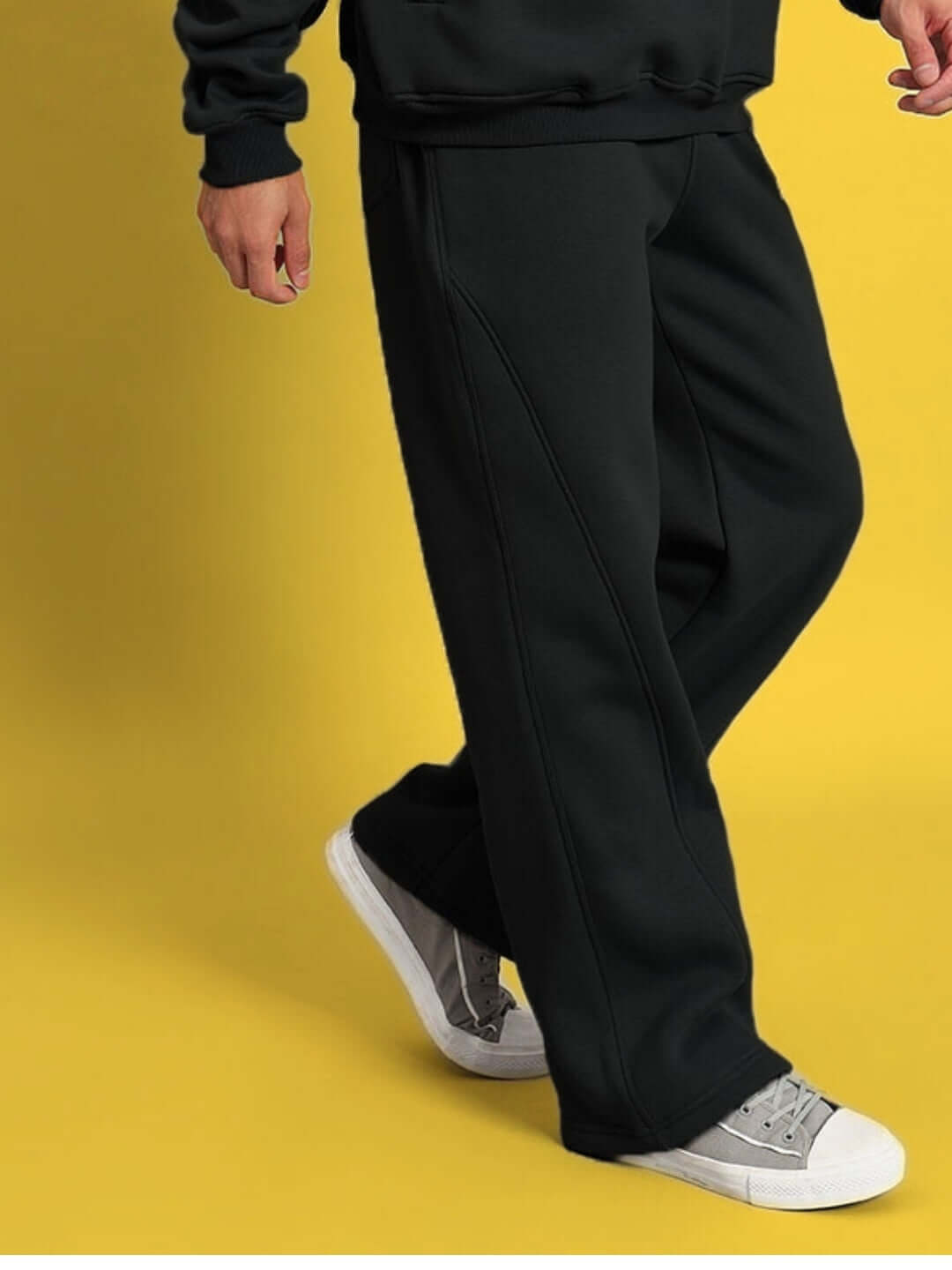 Man wearing WEARDUDS SHOOTER FLEECE PANT BLACK with sneakers on yellow background.