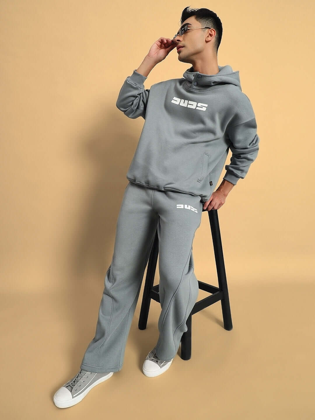 Model wearing SHOOTER COTTON FLEECE PANT GREY showcasing street style and comfort on a beige background.