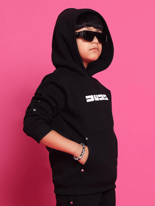 Child wearing SHOOTER HOODIES FOR BOYS GIRLS BLACK, standing confidently against pink background.
