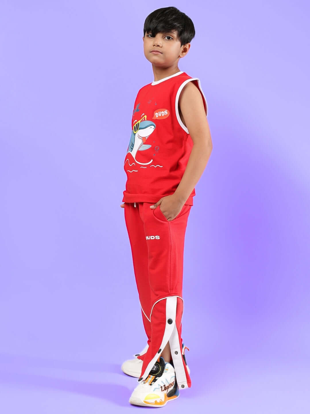 Boy wearing SHORTFIN CO-ORD FOR BOYS & GIRLS RED outfit, standing against a purple background. Fashionable customizable attire for kids.