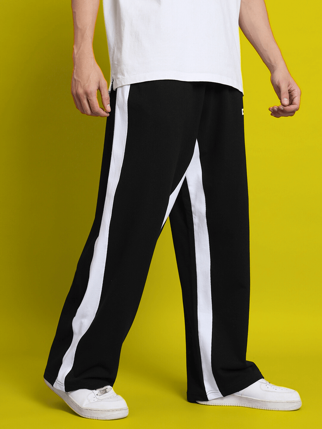 Model wearing SIDE SEAM BAGGY JOGGERS in black with white stripe, made to order by DUDS. Custom fit available for prepaid orders.