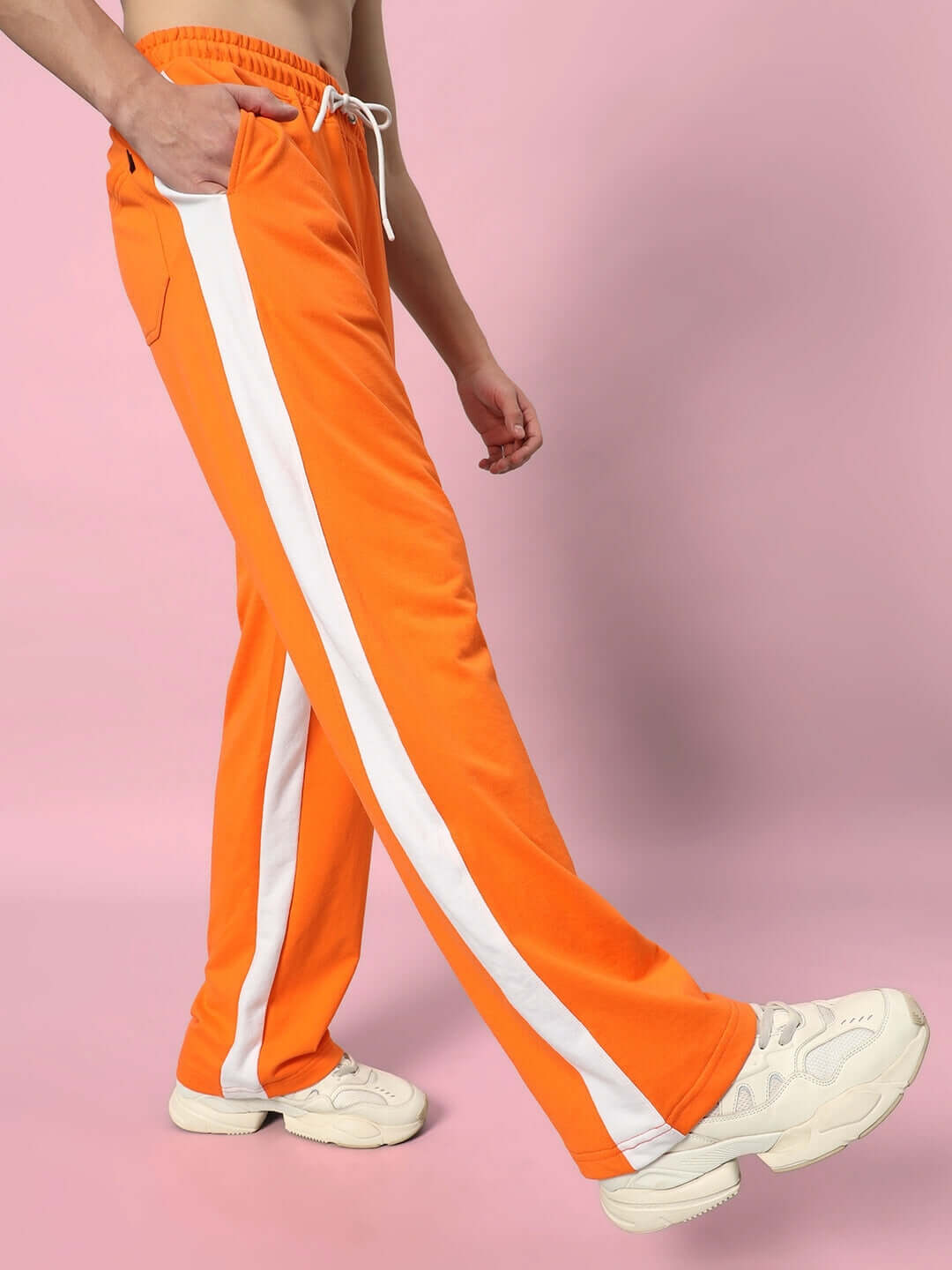 Side seam baggy jogger in vibrant orange with white stripe, showcased on a pink background, custom fit option available.