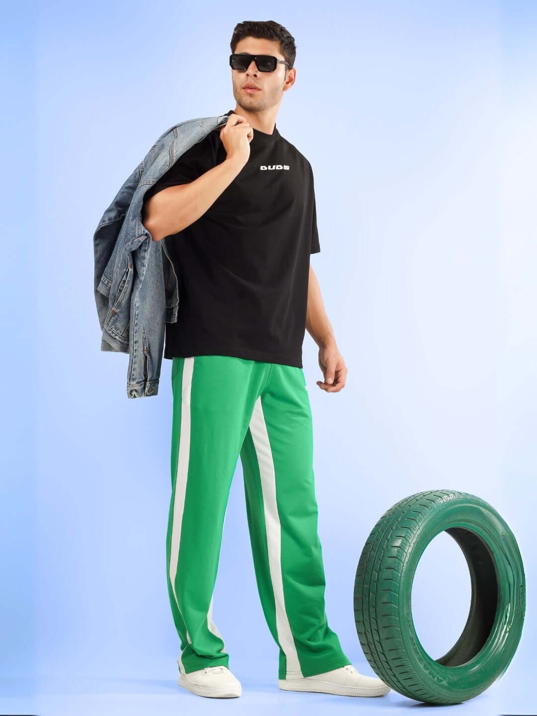 Model wearing green side seam baggy joggers from DUDS, styled with a black top and jacket, perfect for casual outings.