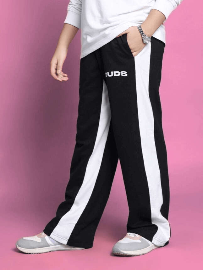 Child wearing unisex oversized joggers with red and white contrast panel, elasticated waistband, and drawstring on a pink background.