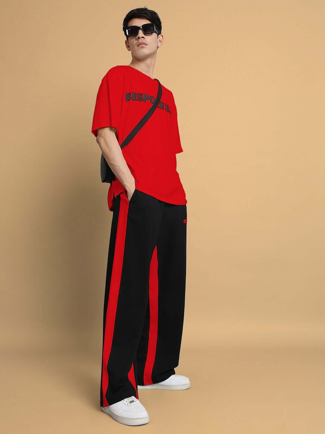 Model wearing black-red side seam baggy joggers with a matching red shirt, showcasing contemporary casual fashion.