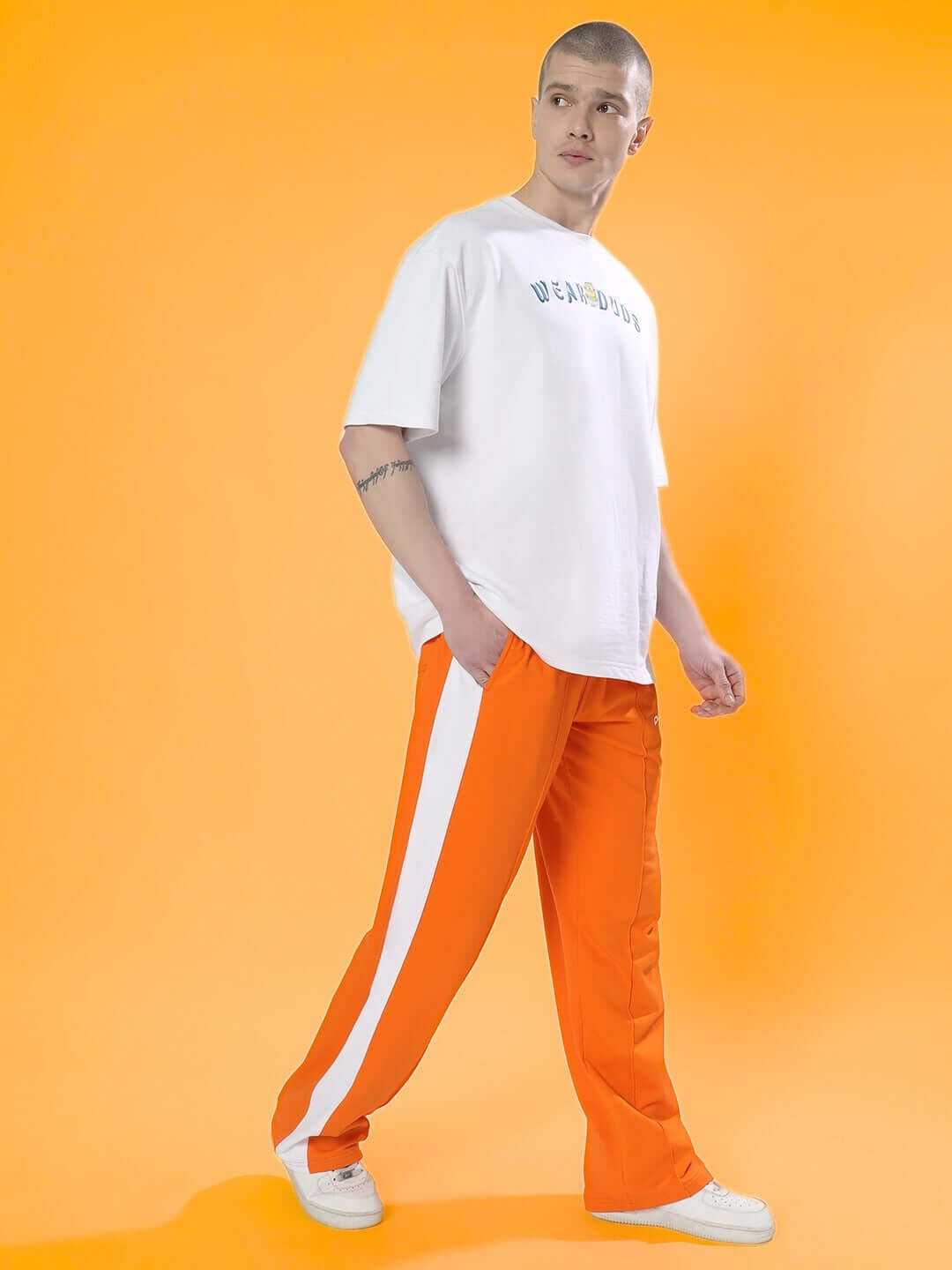 Model wearing orange side seam plated joggers paired with a white tee, showcasing casual style. Perfect for custom fit orders by DUDS.