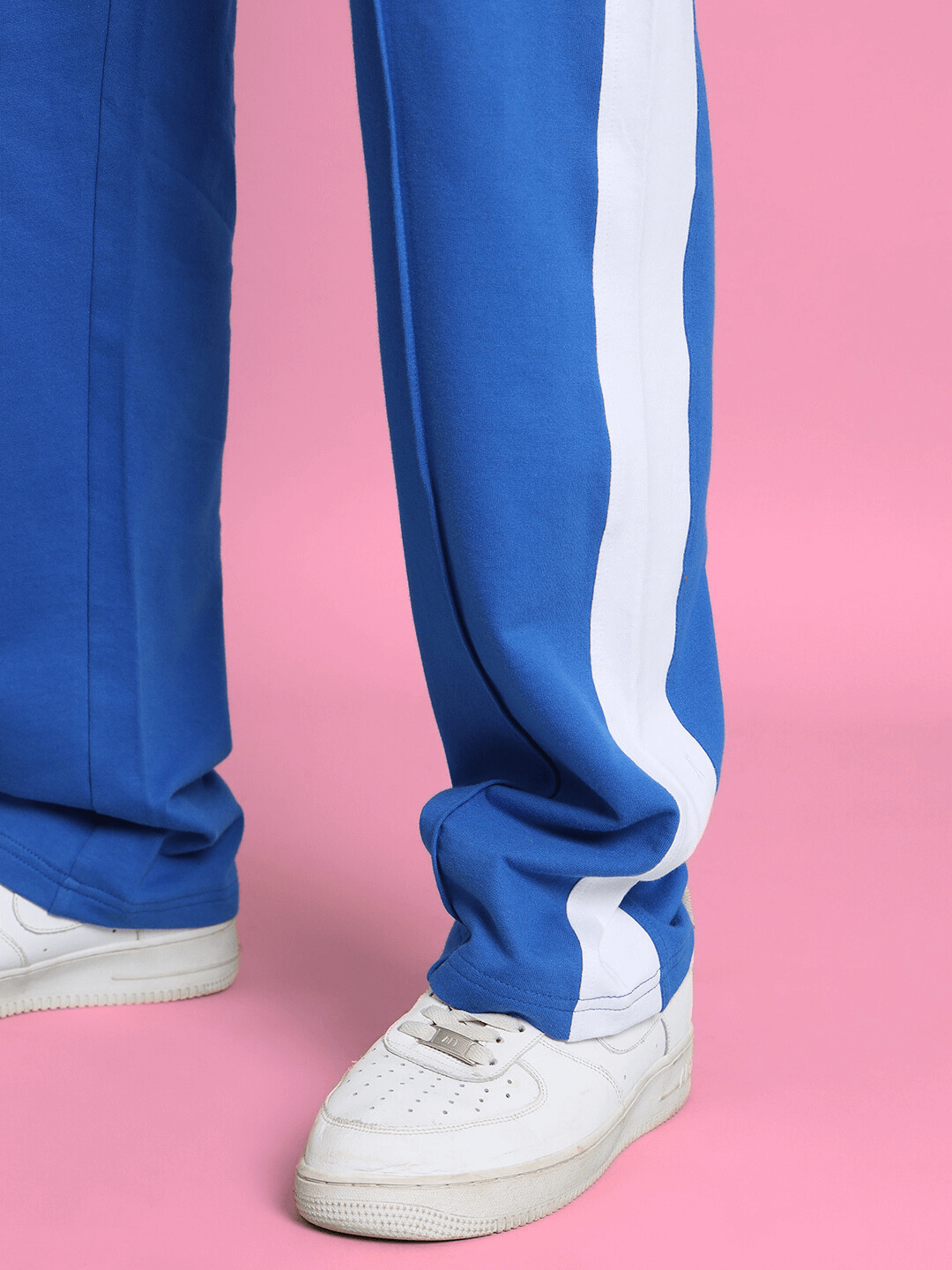 Royal blue side seam plated joggers with white stripe detail, showcased on pink background, paired with white sneakers.
