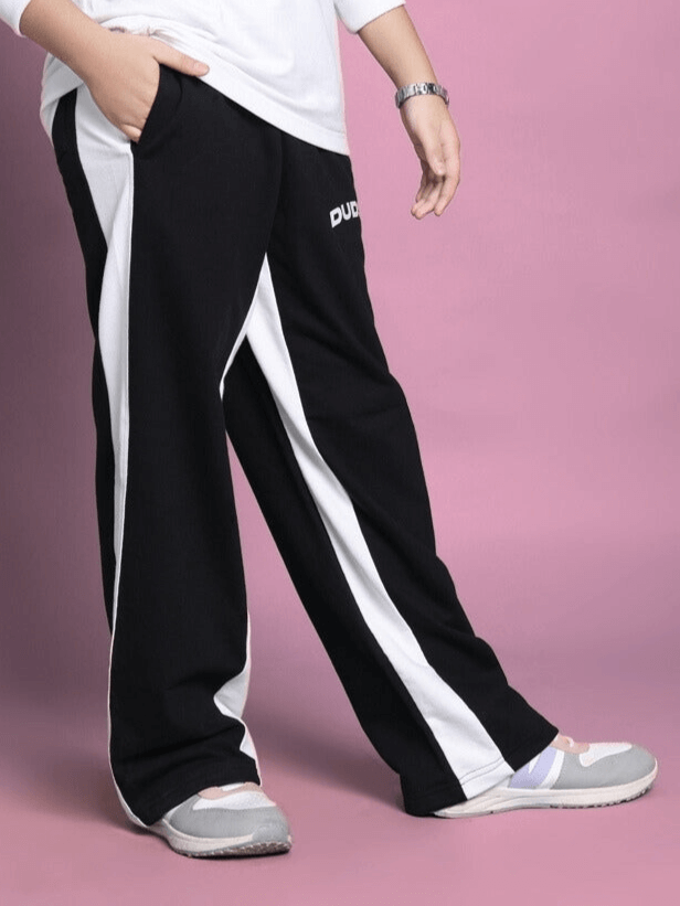 Side seam baggy jogger pants for boys and girls in black with white stripes, worn by a model for DUDS