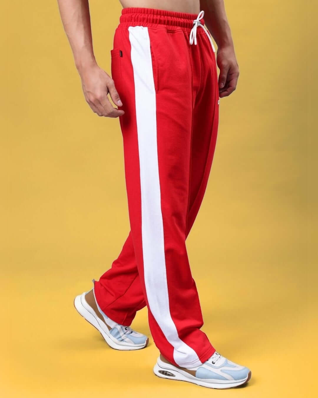 Model wearing red side seam plated joggers with white stripe, styled with sneakers, available for custom fit, tailored by DUDS.