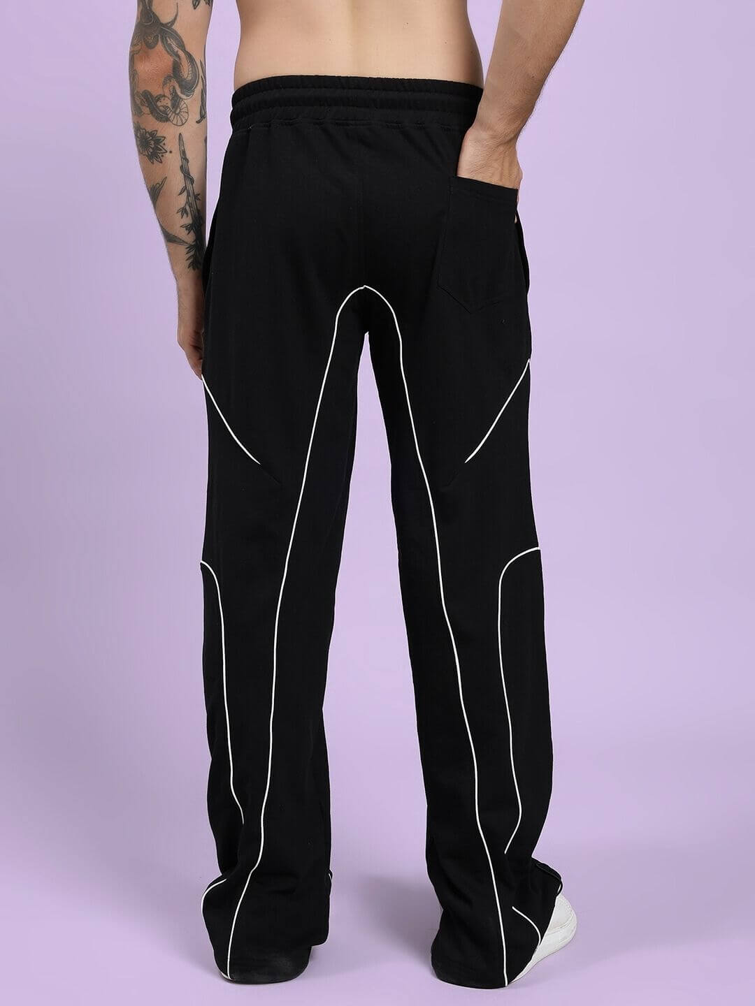 Rear view of a person wearing SIGNATURE PIPING JOGGERS BLACK with contrast piping and relaxed fit, perfect for comfort and style.