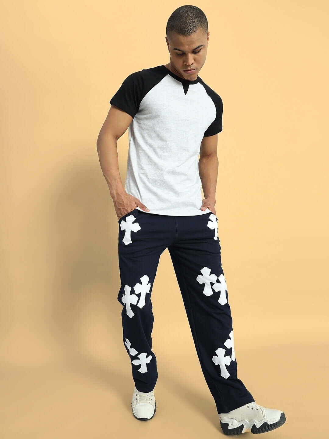 Model wearing Signum Relaxed Joggers in navy blue with white cross patterns, paired with a casual white and black tee, showcasing a stylish look.