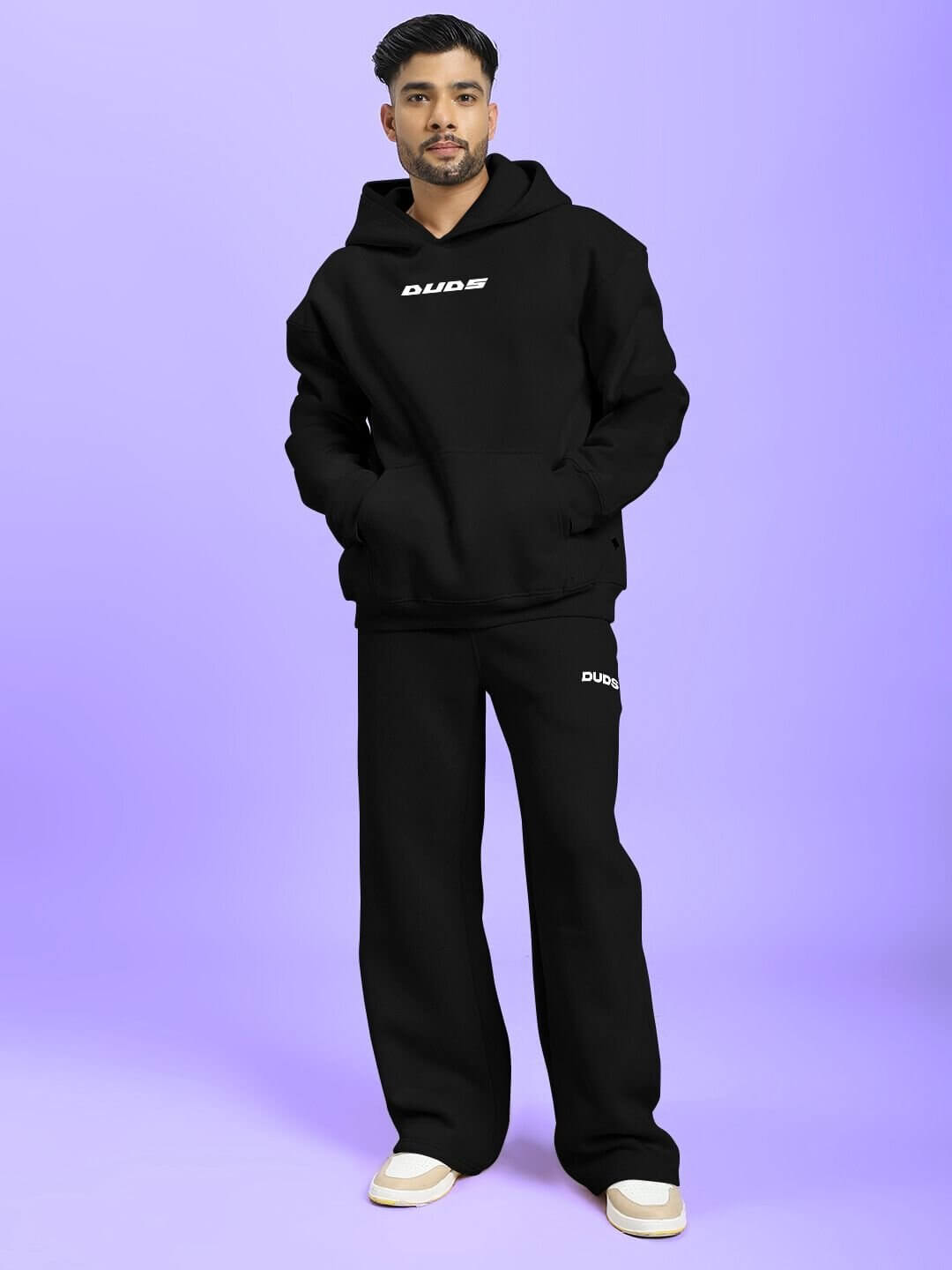 Man wearing SILVER SURFER FLEECE CO-ORD SET BLACK, showcasing streetwear style with casual hoodie and pants on a purple background.