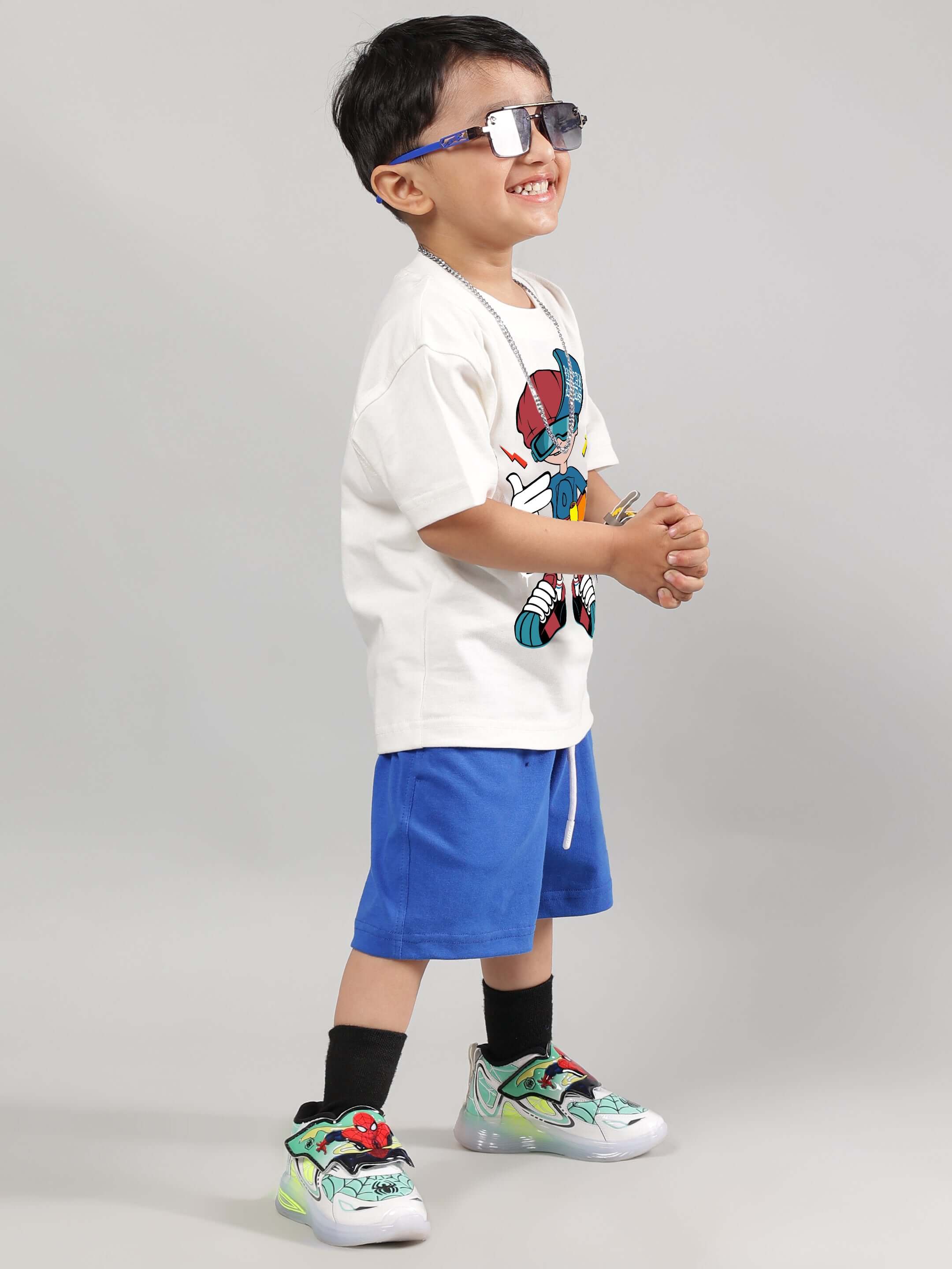 Child wearing SKATE RIDER T-shirt for boys and girls in off-white with blue shorts, showcasing vibrant and playful style.