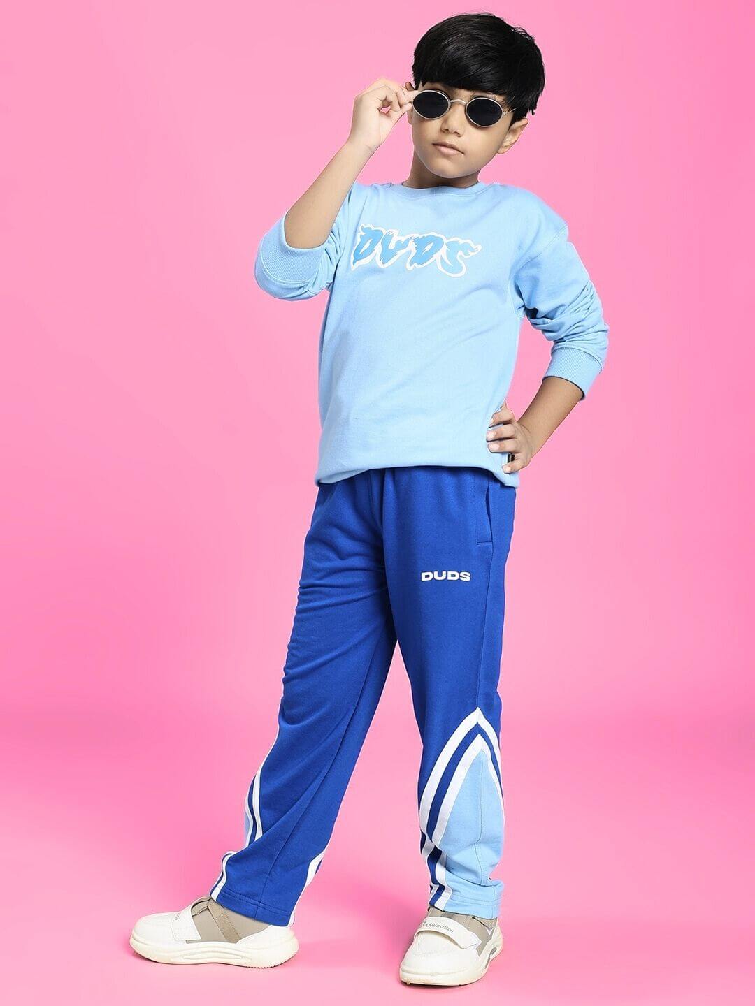 Child wearing SKATER DUCK SWEATSHIRT FOR BOYS AND GIRLS SKY BLUE posing stylishly against pink background.