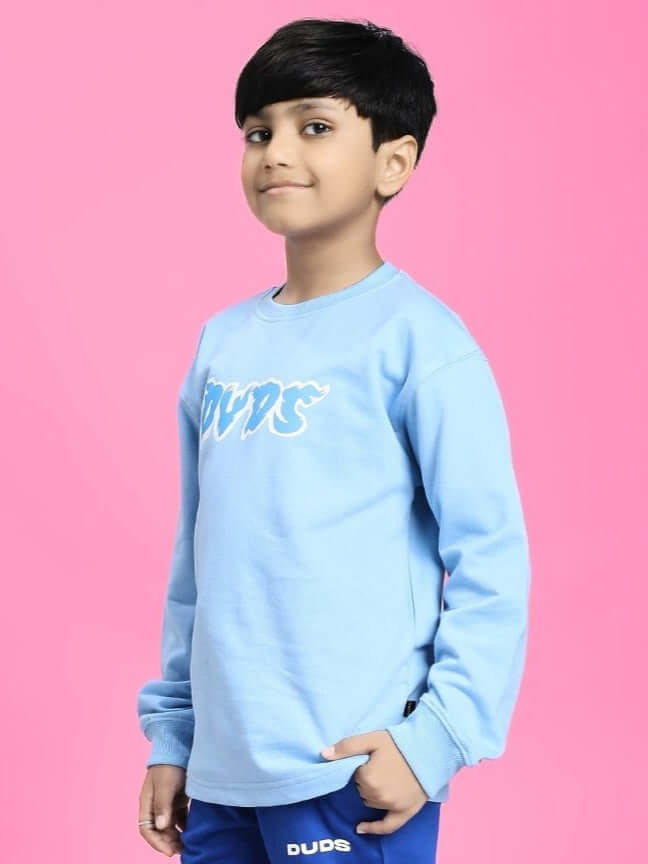 Boy wearing SKATER DUCK SWEATSHIRT FOR BOYS AND GIRLS SKY BLUE against pink background