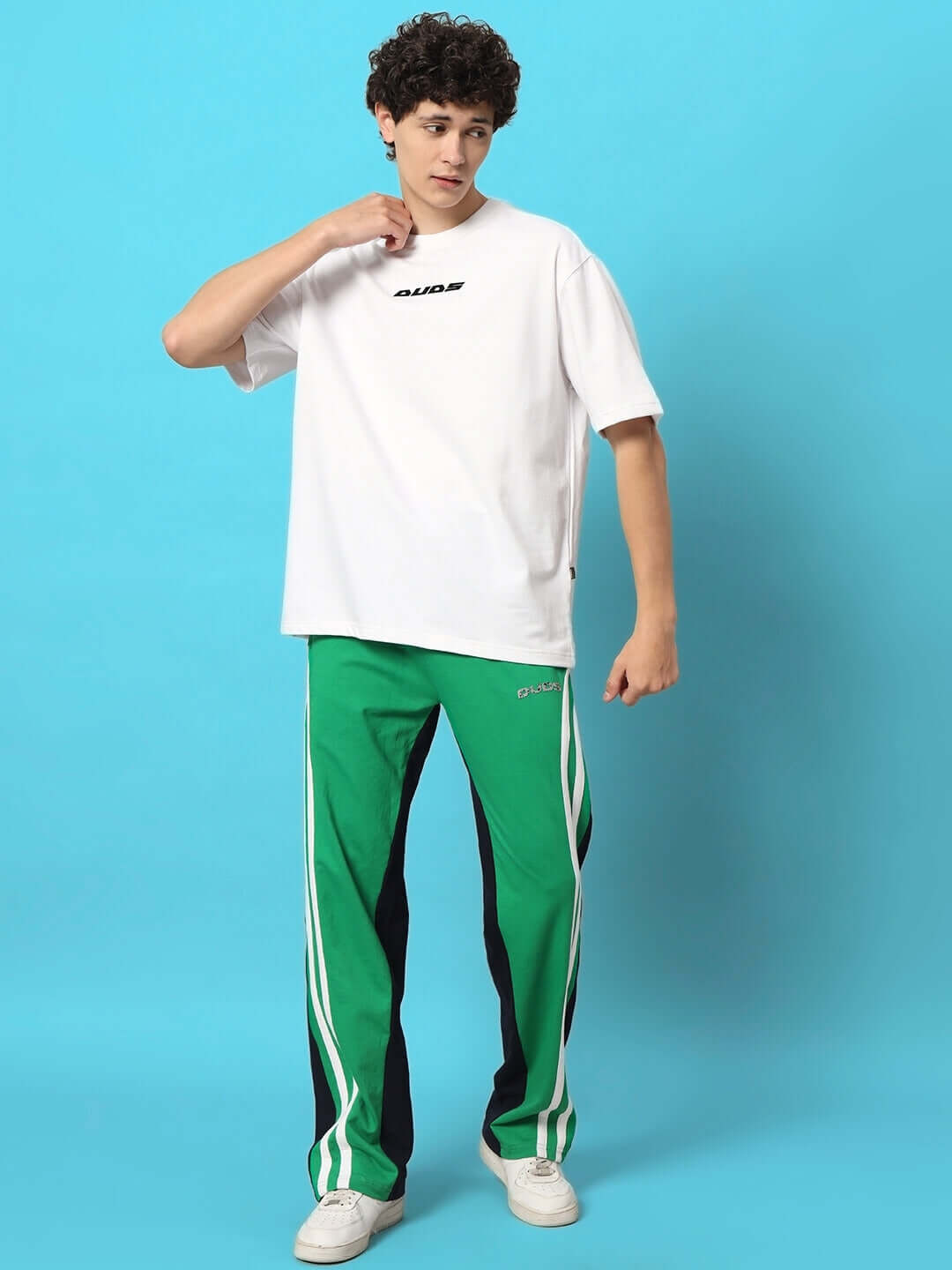 Man wearing DUDS Skater Korean Baggy Joggers in green and black with a white t-shirt, posing against a blue background.