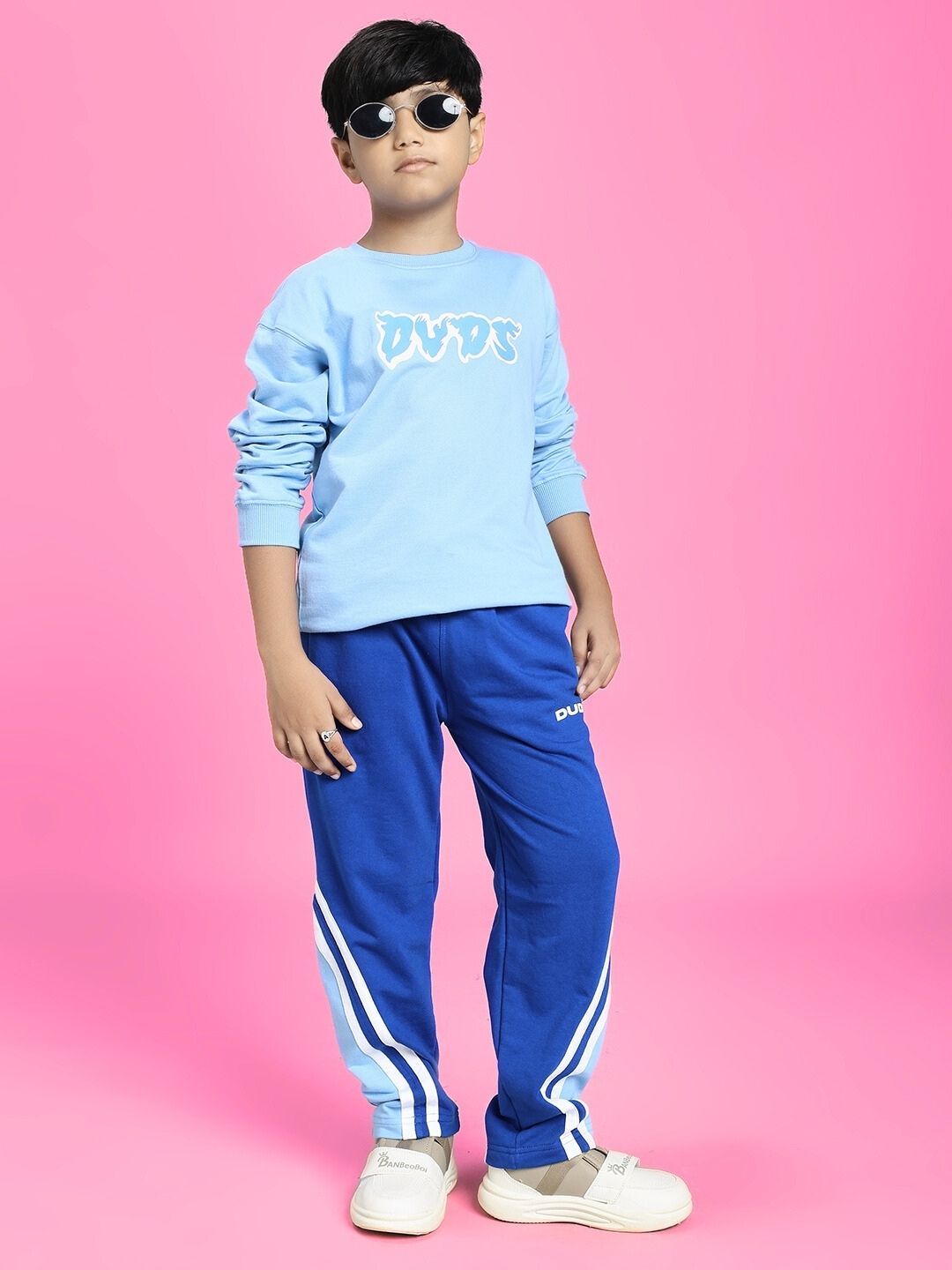 Child wearing a SKATER DUCK SWEATSHIRT FOR BOYS AND GIRLS SKY BLUE with blue pants on a pink background.