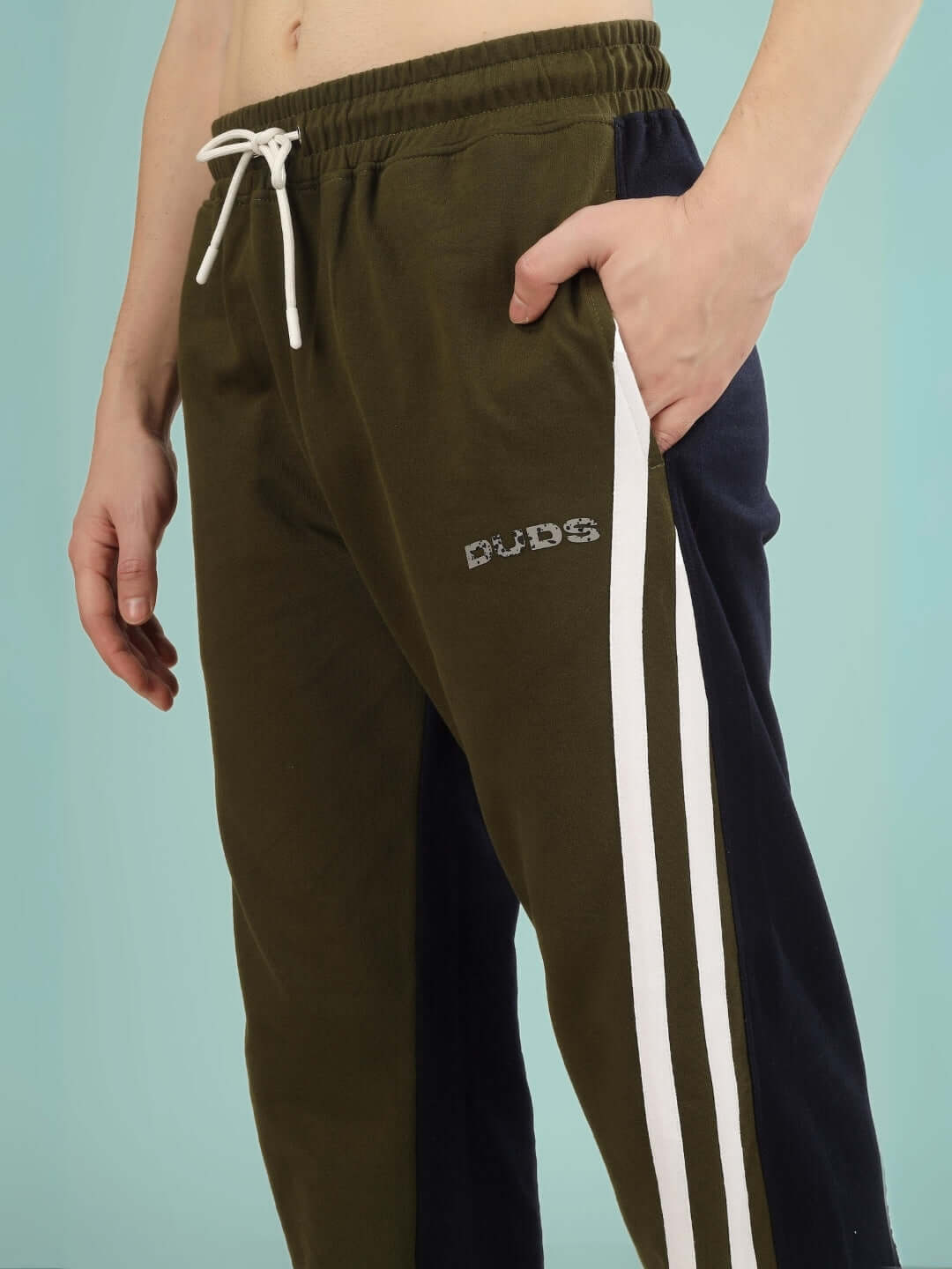 Model wearing olive navy skater Korean baggy joggers with DUDS logo, featuring white side stripes and drawstring waist.