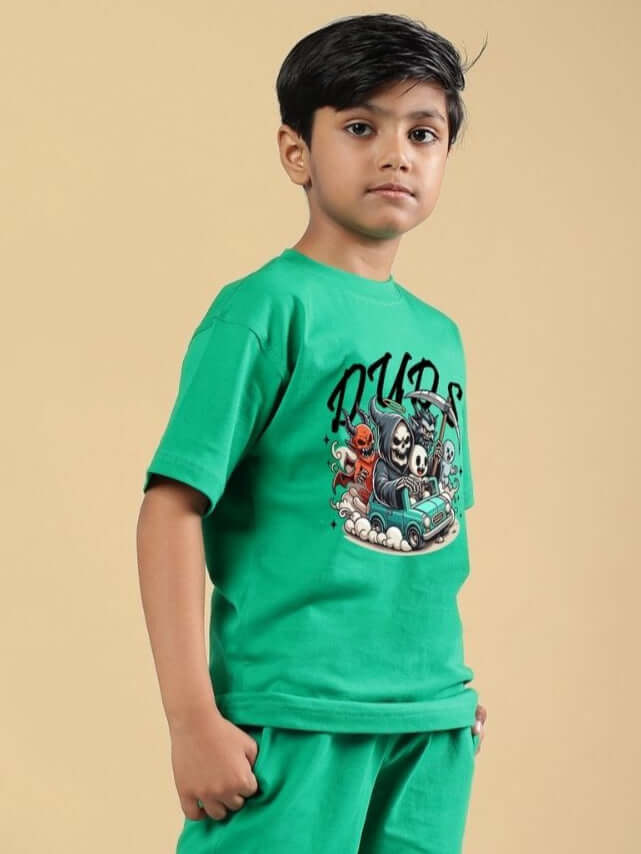 Boy wearing Skeleton Rider Car Print T-Shirt for Boys and Girls Green, featuring an edgy car and skeleton design, on a beige background.