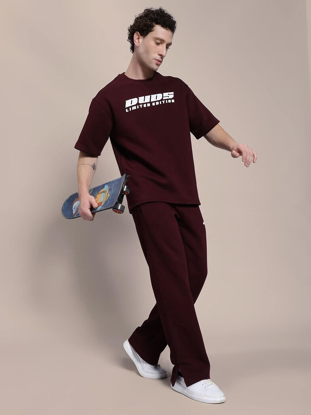 Man wearing SKODA COTTON FLEECE JOGGER MAROON with skateboard, showcasing street-smart style and comfort.