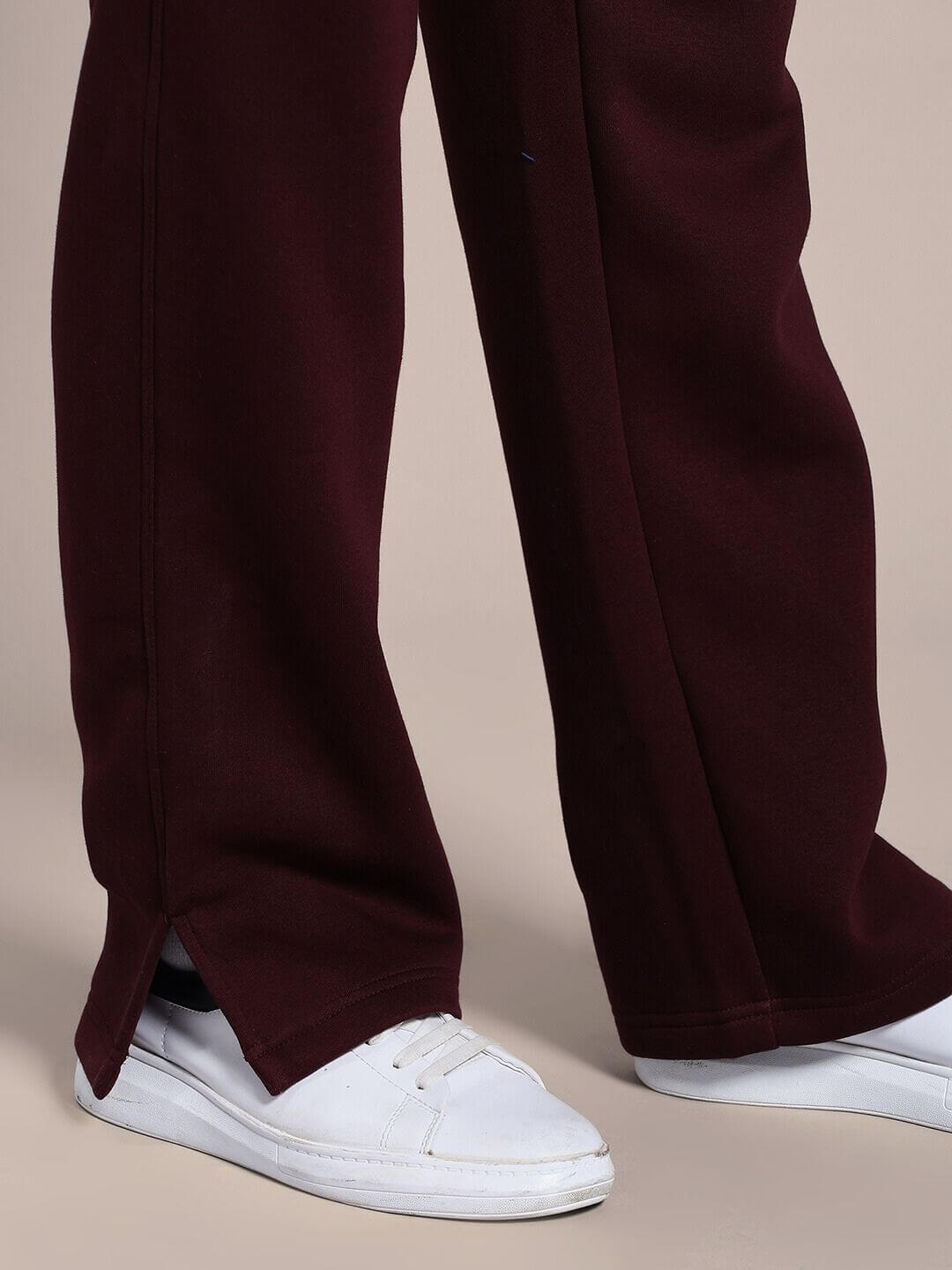Person wearing SKODA COTTON FLEECE JOGGER MAROON with white sneakers, showcasing rich maroon fabric and urban casual style.