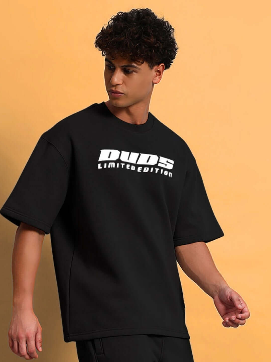 Model wearing SKODA FLEECE OVERSIZED T-SHIRT BLACK with a bold streetwear style on a colorful background.