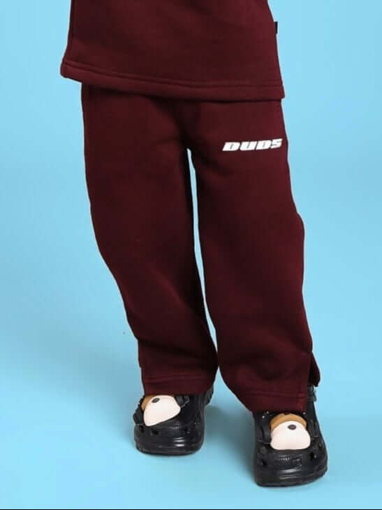 Child wearing SKODA FLEECE JOGGER FOR BOYS AND GIRLS MAROON standing on blue background