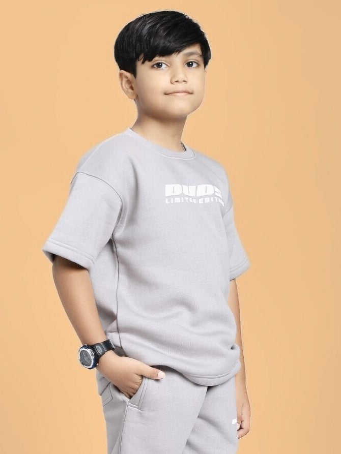 Boy wearing grey SKODA FLEECE T-SHIRT FOR BOYS AND GIRLS GREY with a stylish look on a peach background.
