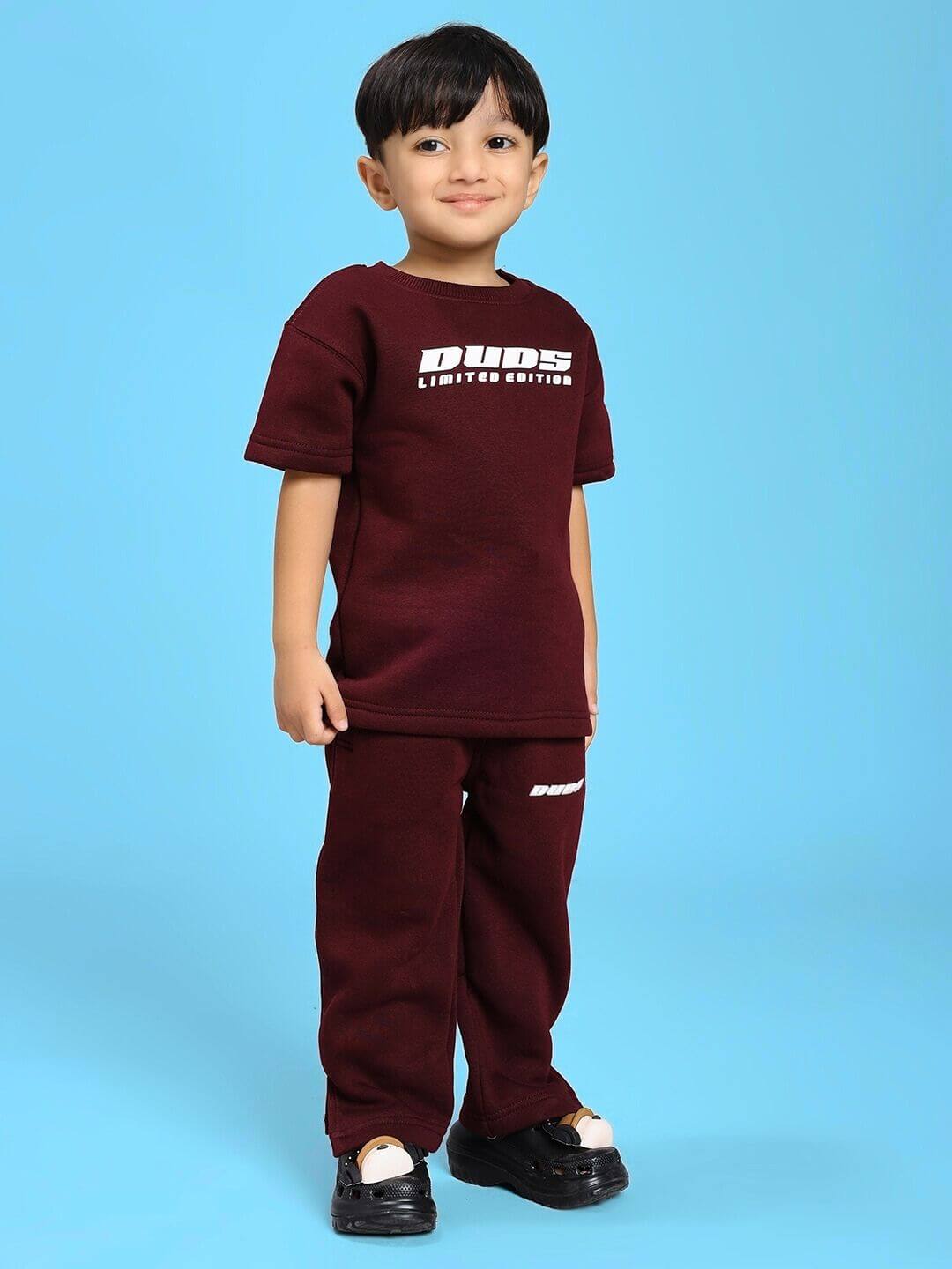 Child wearing SKODA FLEECE T-SHIRT FOR BOYS AND GIRLS MAROON against blue background