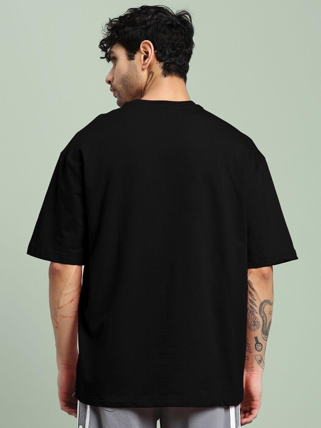 Back view of a person wearing a SKULL BLAST FIRE PRINT OVERSIZED T-SHIRT BLACK, showcasing its oversized fit and cotton fabric quality.