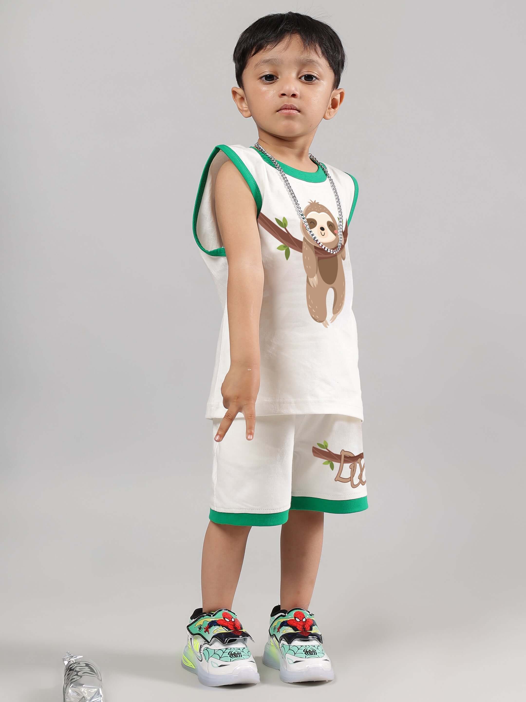 Child wearing off-white sloth-themed shorts and top set from DUDS, featuring green trim and sloth graphic, made to order by skilled tailors.