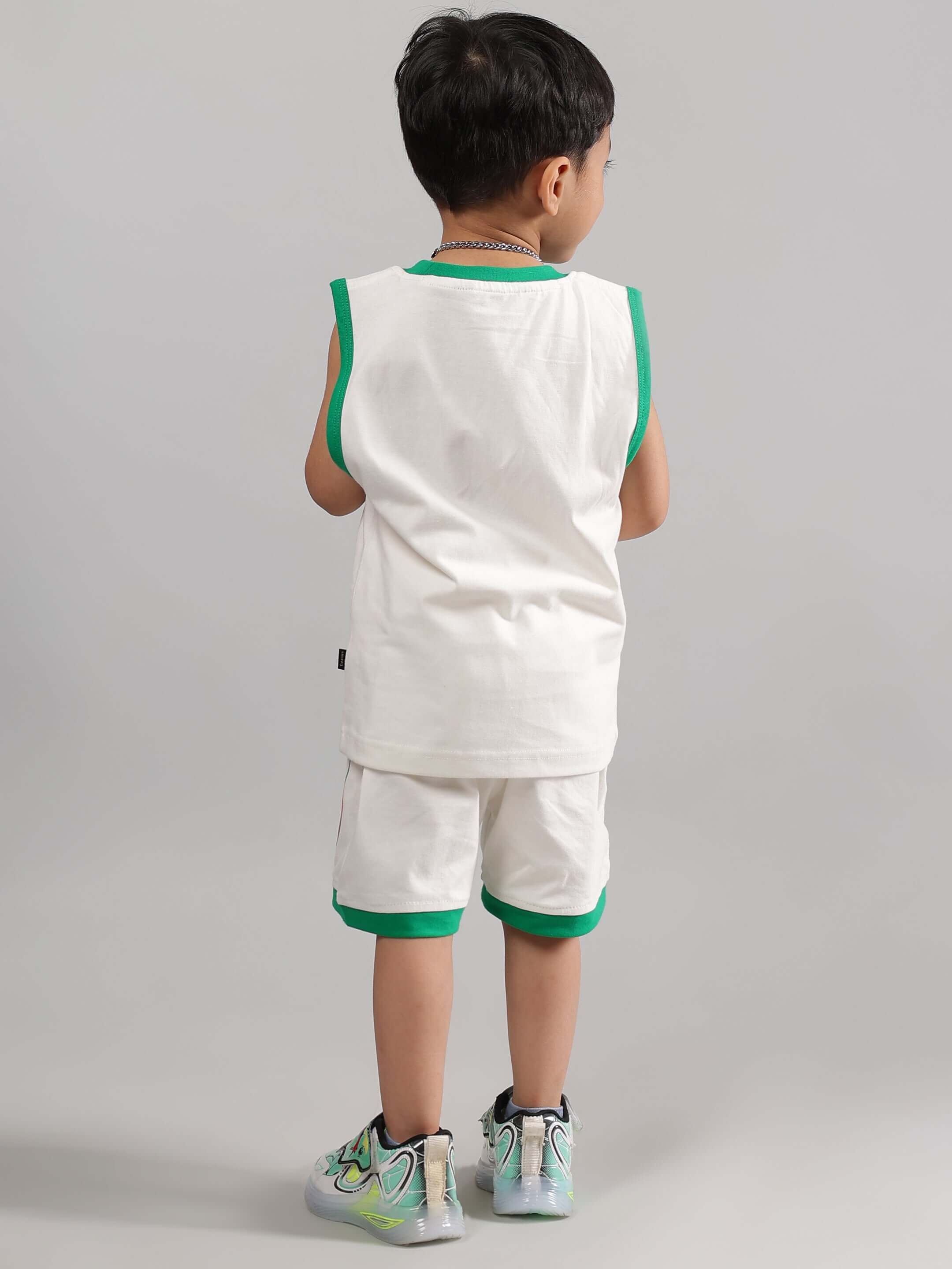Child wearing off-white sloth shorts set for boys and girls, green trim detailing, perfect for custom fitting by DUDS tailors.