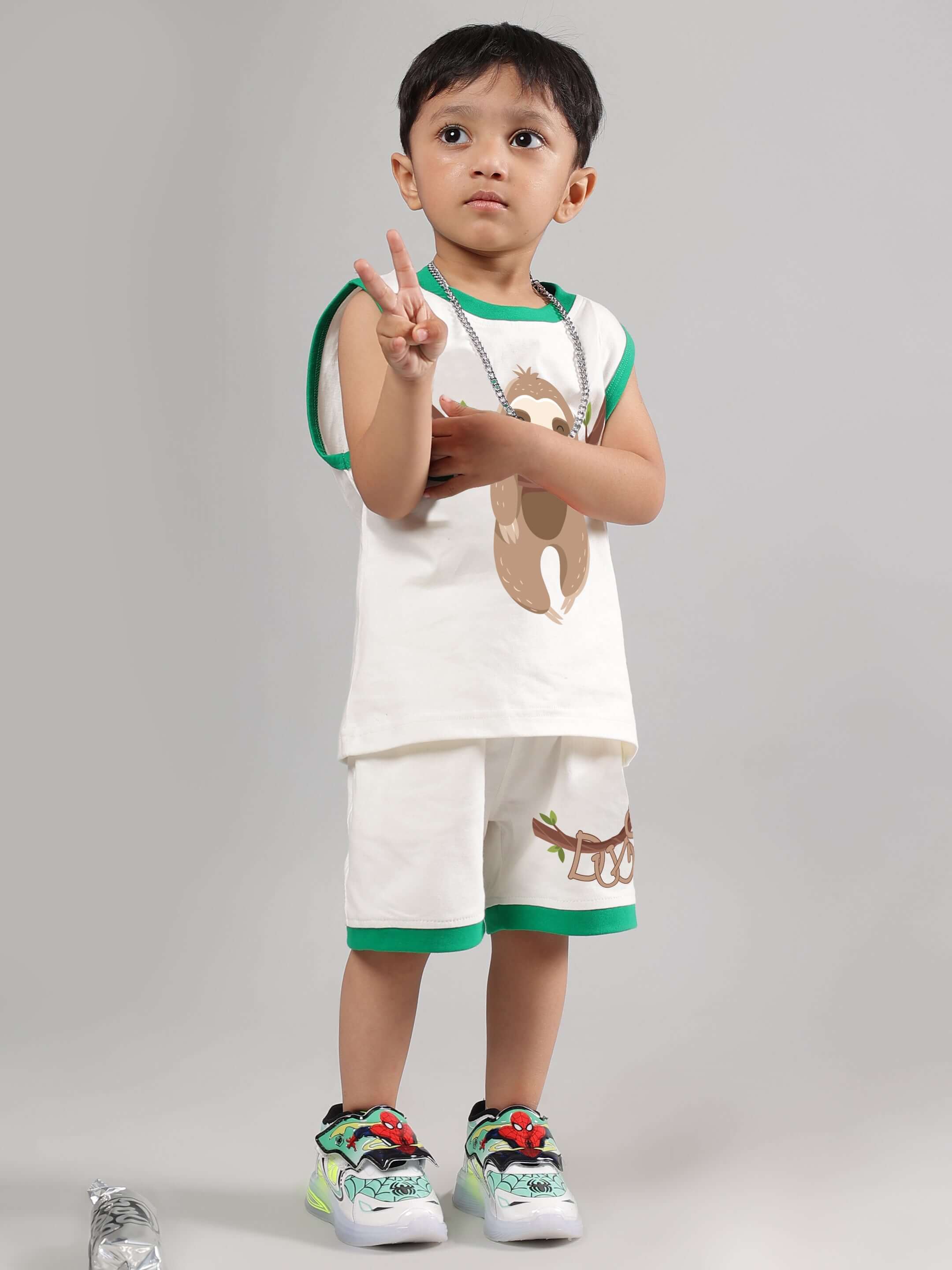Young child wearing off-white sloth t-shirt and shorts set, making a peace sign. Ideal unisex apparel for boys and girls.