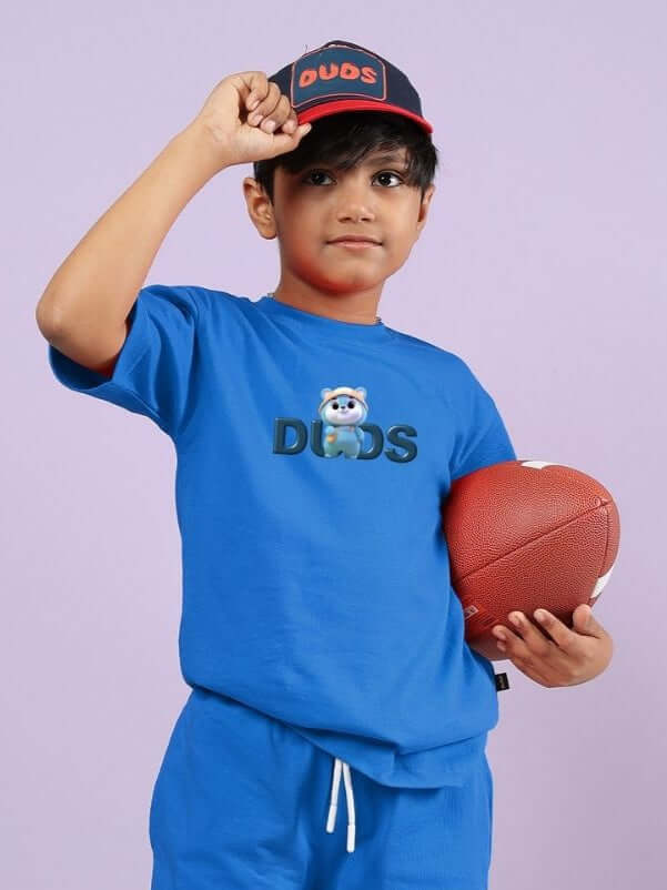 Child wearing SMILEY BEAR T-SHIRT FOR BOYS AND GIRLS BLUE with a football, smiling.