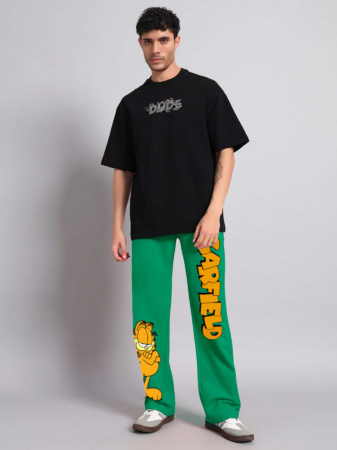 Model wearing SMUG GARFIELD Relaxed Fit Jogger, green pants with Garfield graphic, paired with black DUDS t-shirt.