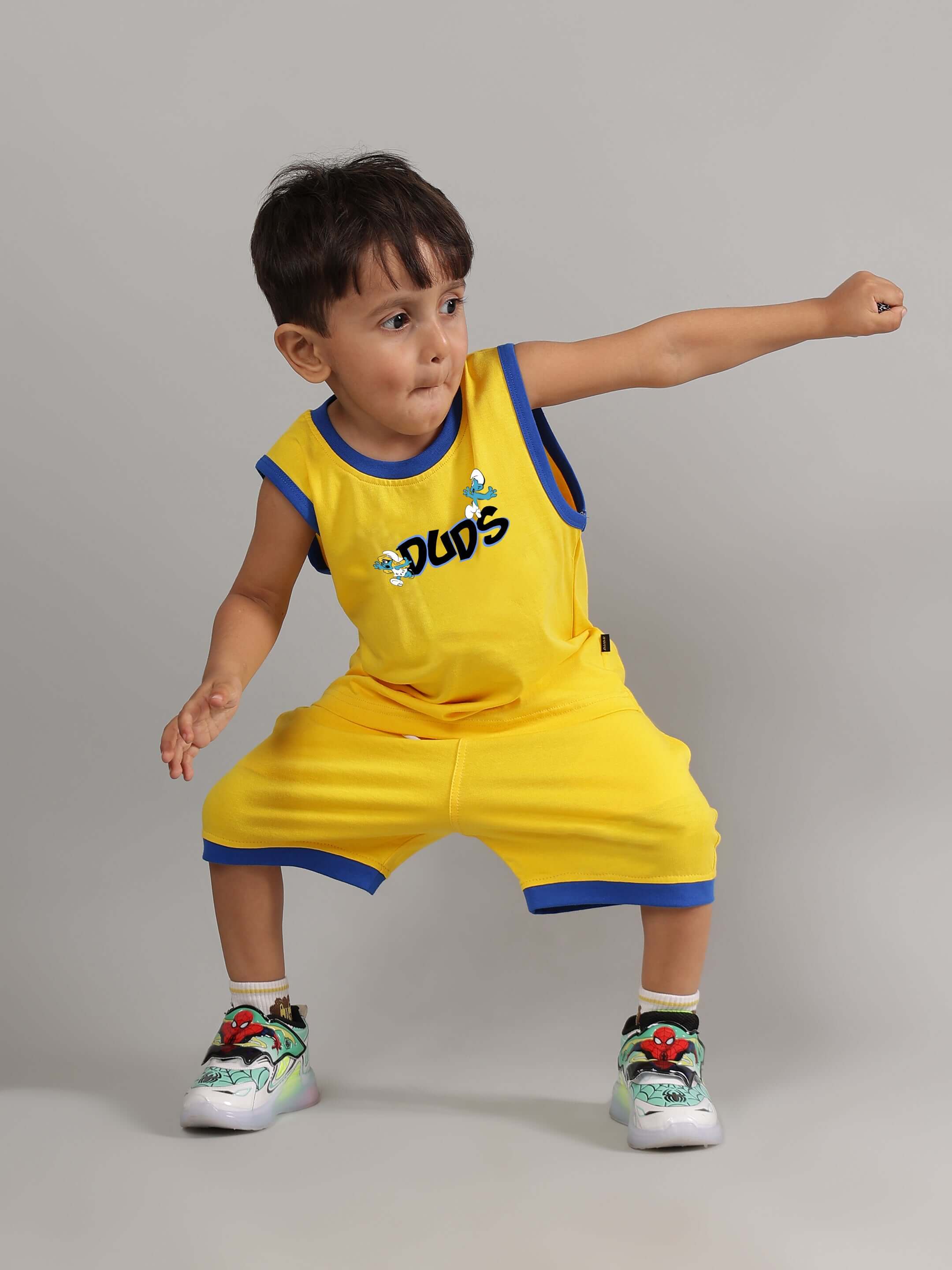 Child wearing a yellow Smurfs Home T-shirt for boys and girls, designed by DUDS, demonstrating a playful pose.