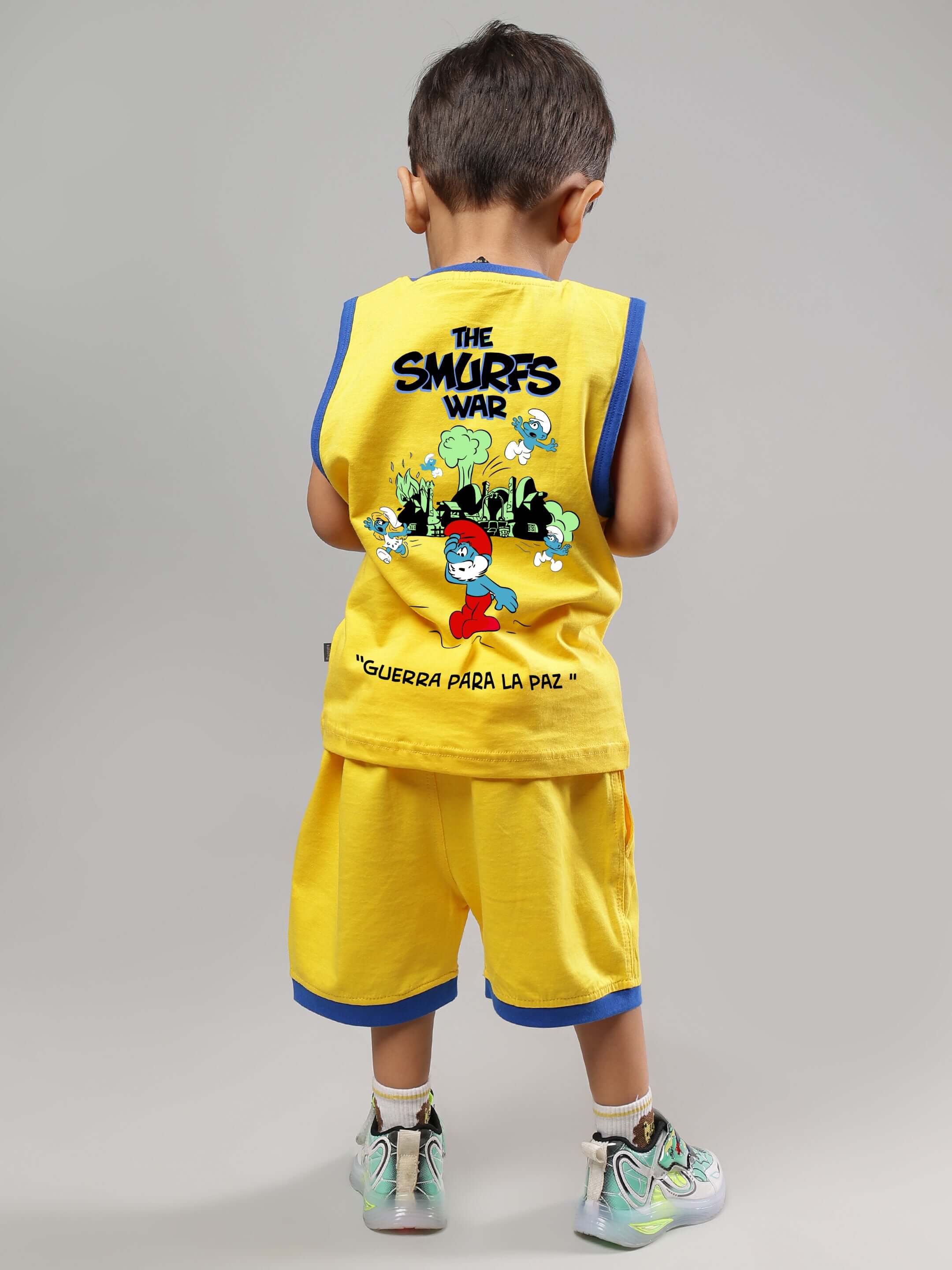 Child wearing a yellow Smurfs Home T-shirt and shorts set, featuring Smurfs characters, standing with their back facing the camera.