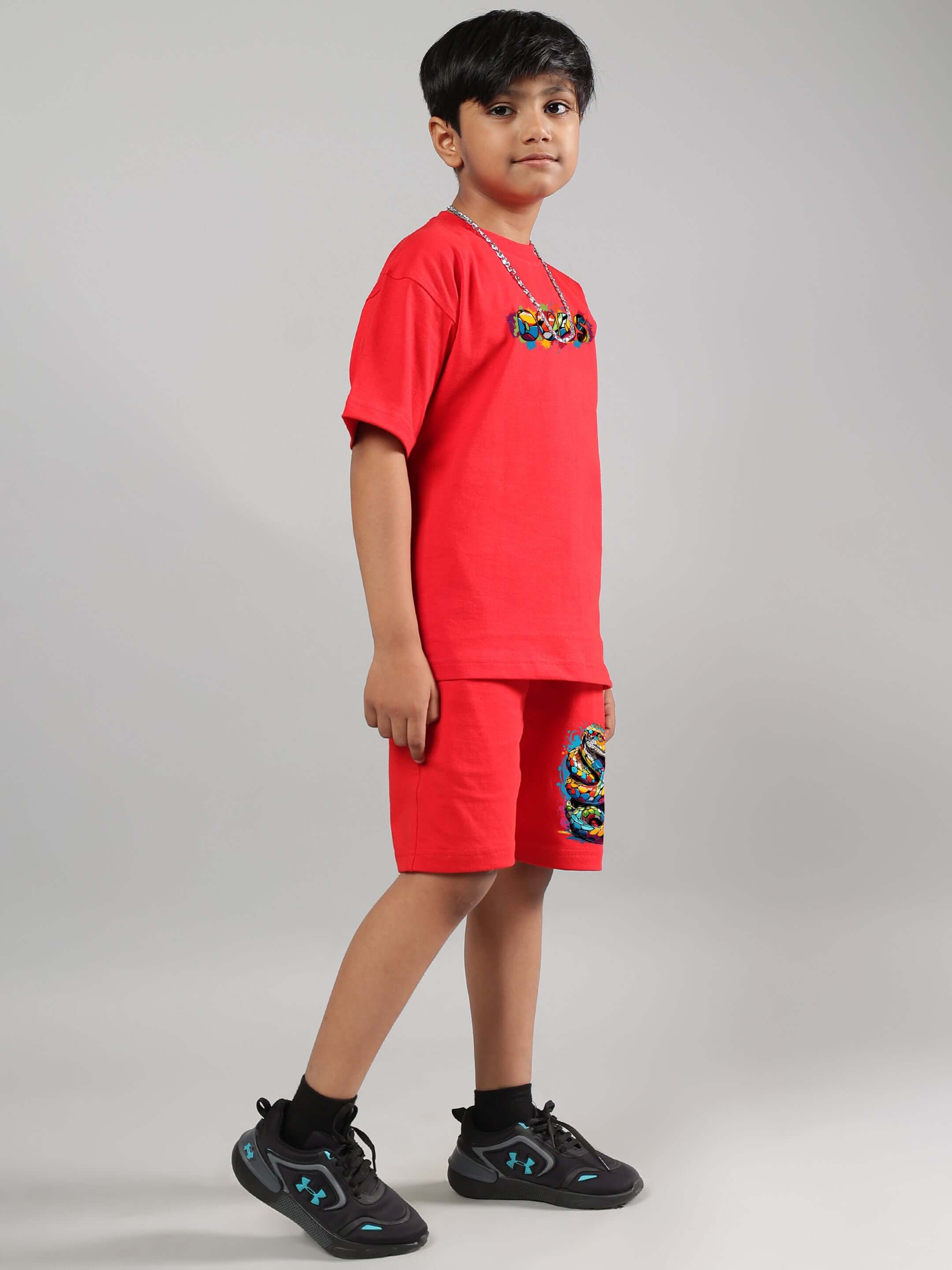 Child wears a red snake skin t-shirt and shorts set, standing confidently. Handmade by DUDS, customizable for boys and girls.