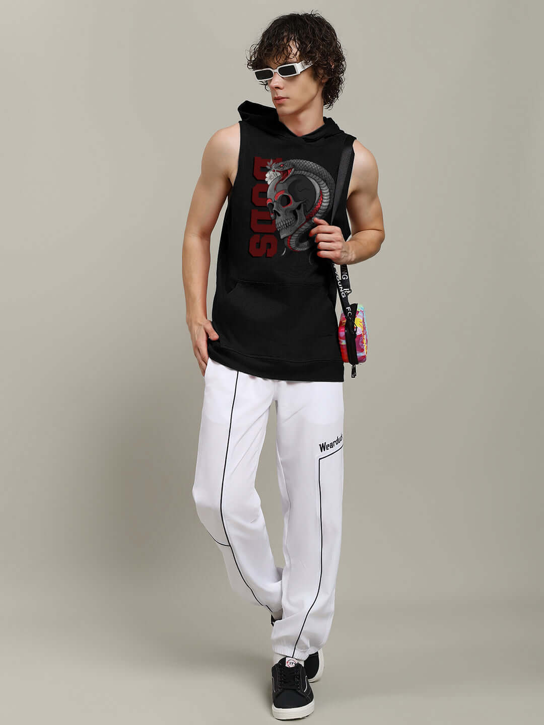 Man wearing black Snake & Skull Gym Hooded T-Shirt with bold graphic, paired with white pants and sunglasses, showcasing sporty style.