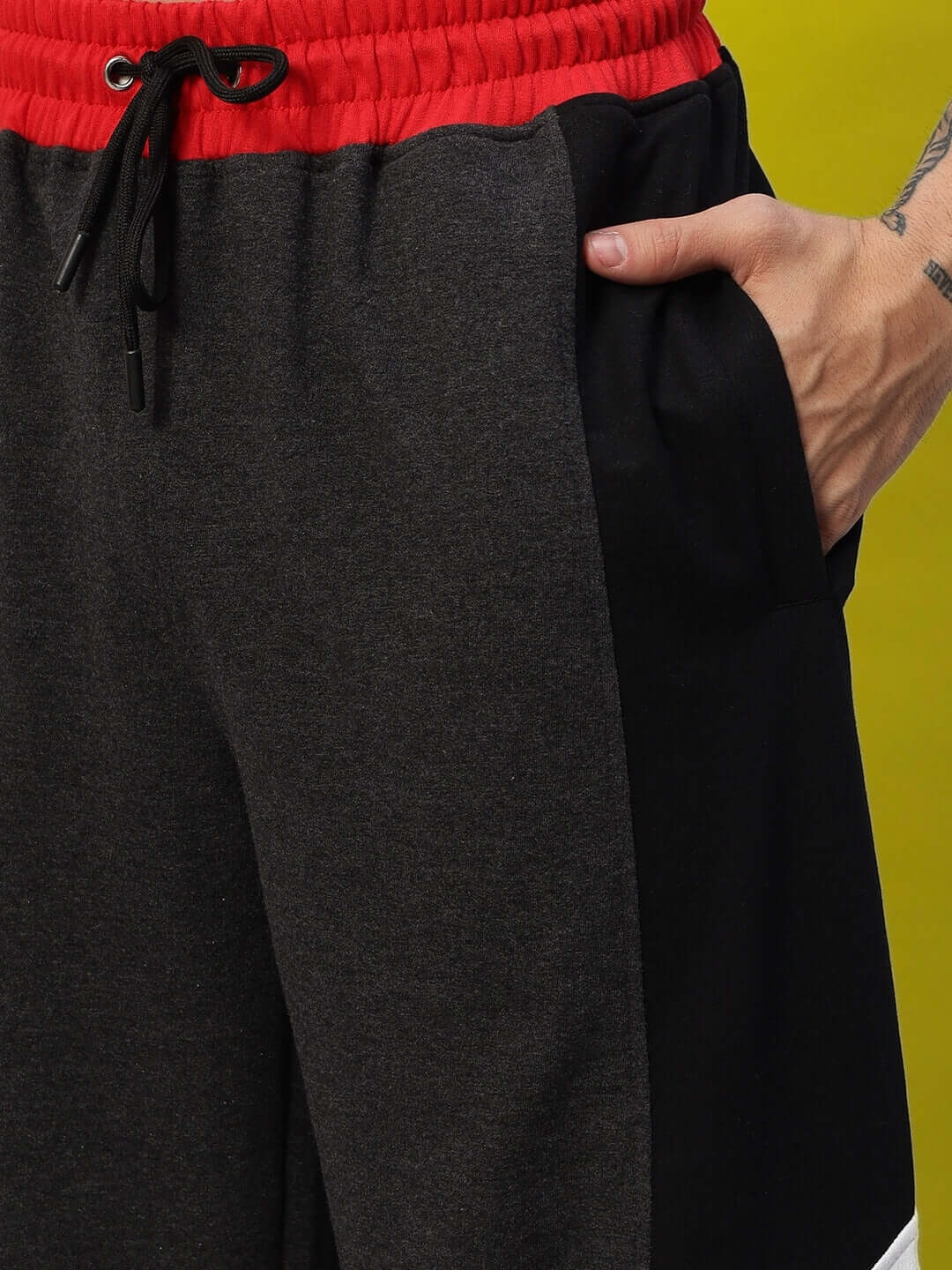 Person wearing Snicker Relaxed-Fit Joggers in dark grey with red waistband, showcasing pocket detail.