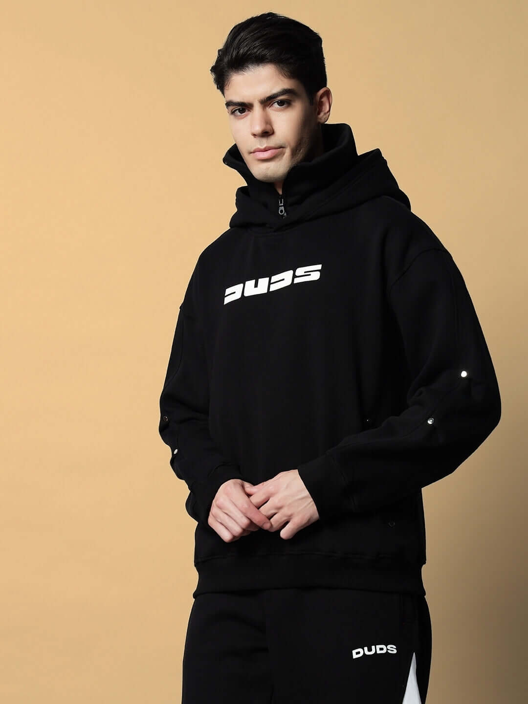 SNIPPER COTTON FLEECE HOODIE BLACK worn by a model, showcasing its relaxed fit, spacious hood, ribbed cuffs, and kangaroo pocket.