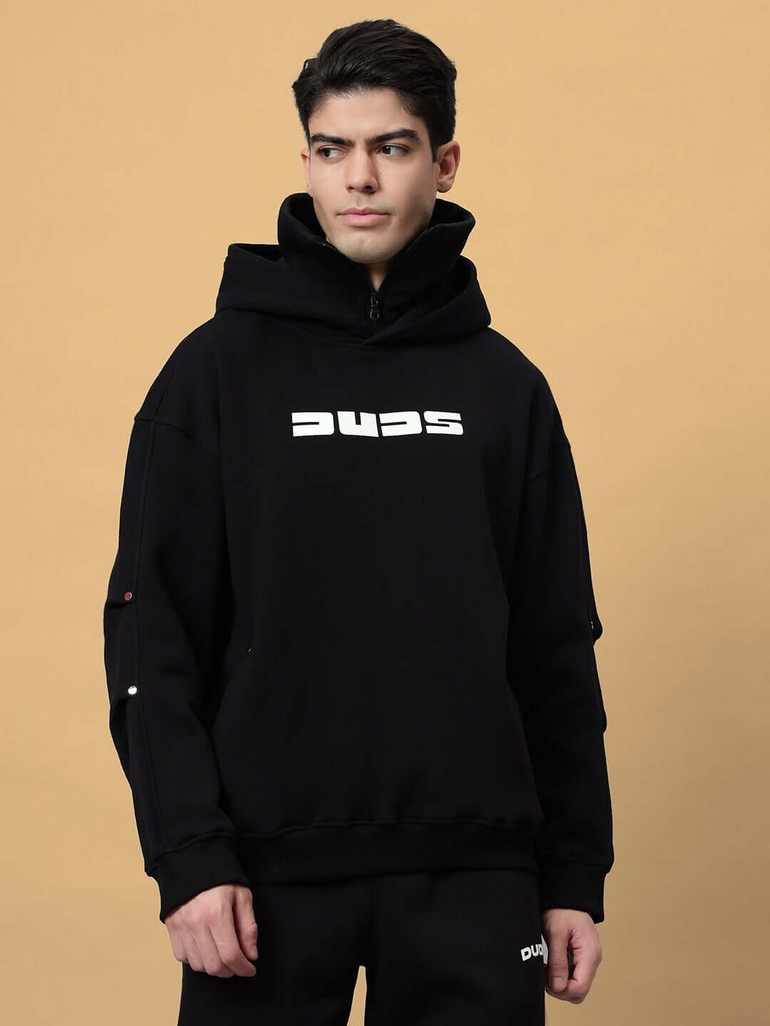 Man wearing SNIPPER COTTON FLEECE HOODIE BLACK, featuring a spacious hood, ribbed cuffs, and classic kangaroo pocket for streetwear style.