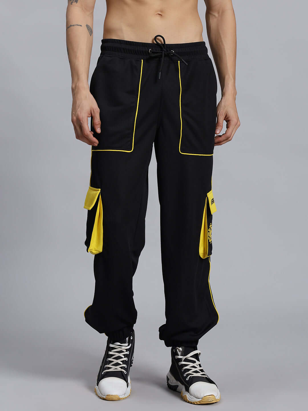 SOCCER REGULAR FIT CARGO JOGGER BLACK Model wearing black soccer regular fit cargo joggers with yellow accents and pockets, by DUDS, showcasing customizable fit options.