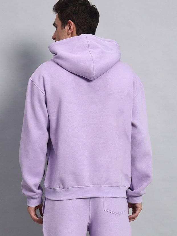 Back view of a person wearing a lavender solid oversized hoodie, showcasing a relaxed fit and classic hood design for casual comfort.