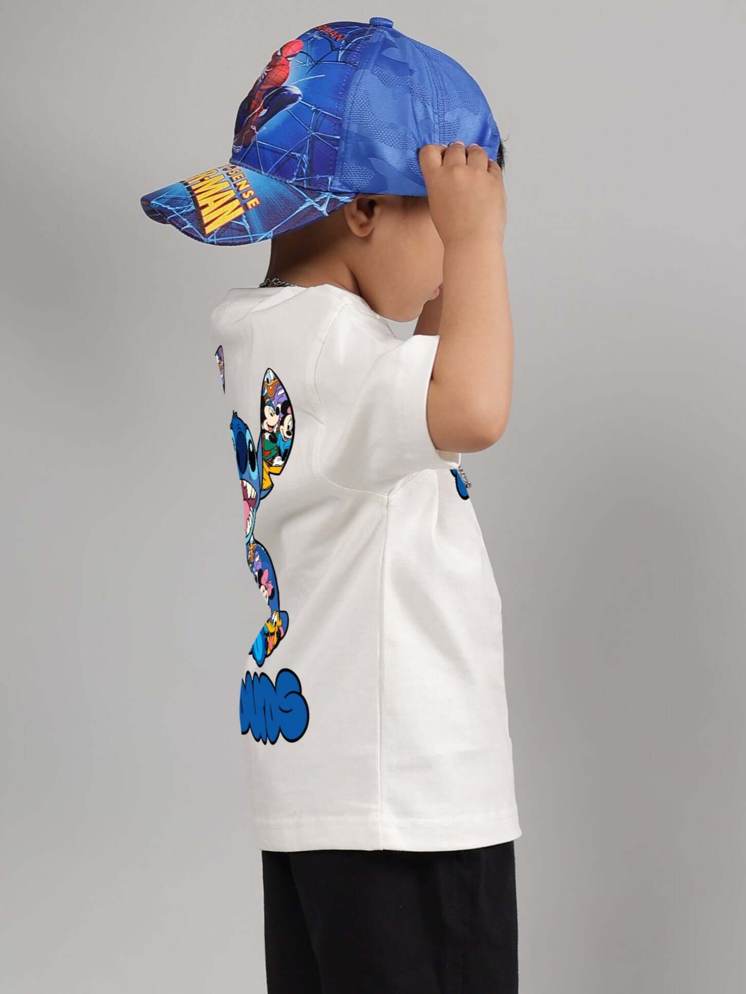 Child wearing SORE T-SHIRT FOR BOYS GIRLS OFF WHITE with comic design, paired with a blue superhero cap.