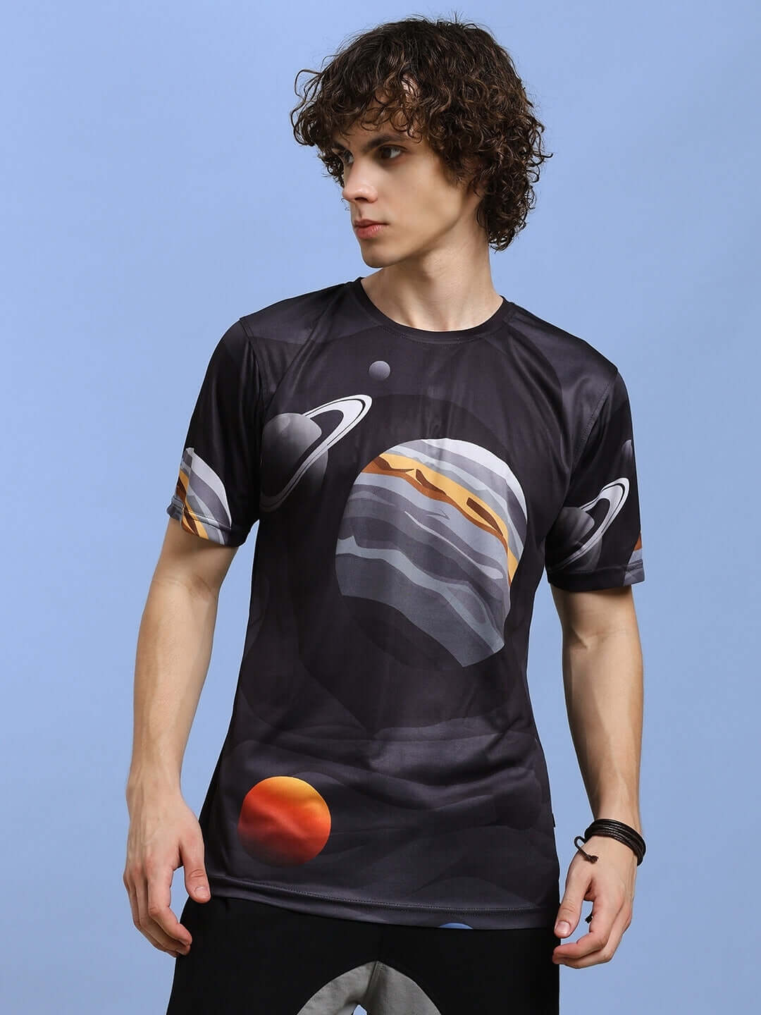 Man wearing a black space-themed t-shirt with planet prints, made from sports polyester fabric. Cold machine wash recommended.