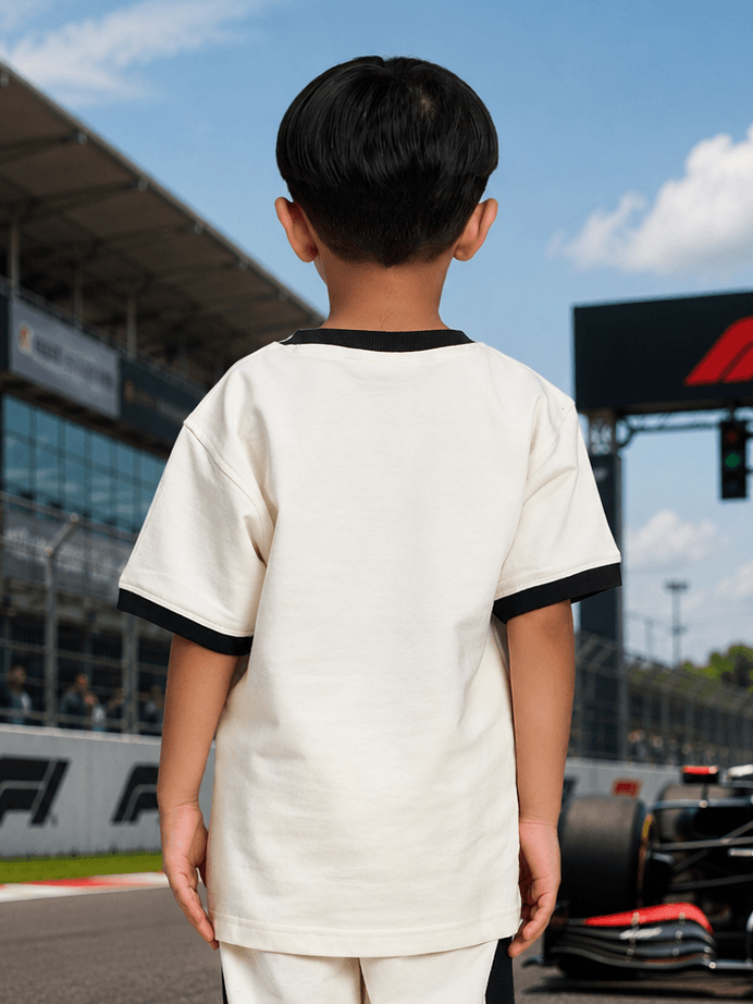 Back view of a child wearing a SPEED SURGE T-SHIRT FOR BOYS GIRLS WHITE at a racetrack.