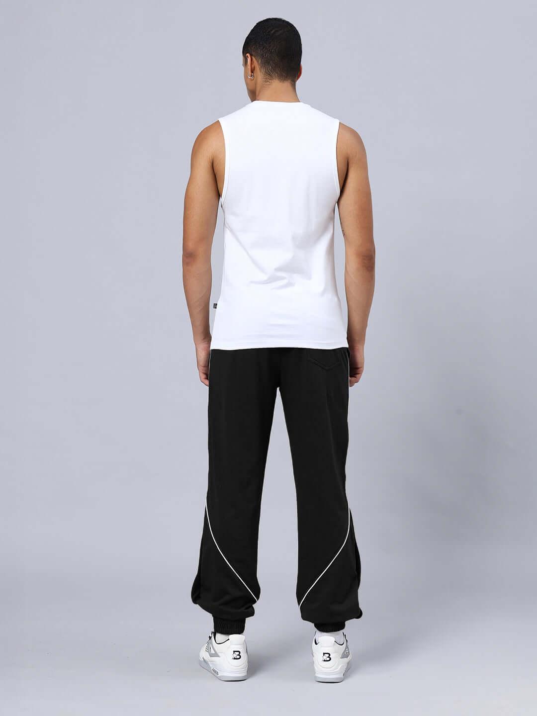 Back view of SPIDER PRINTED GYM RELAXED FIT CO-ORD SET WHITE-BLACK showing unisex fit in white tank and black joggers with sneakers.