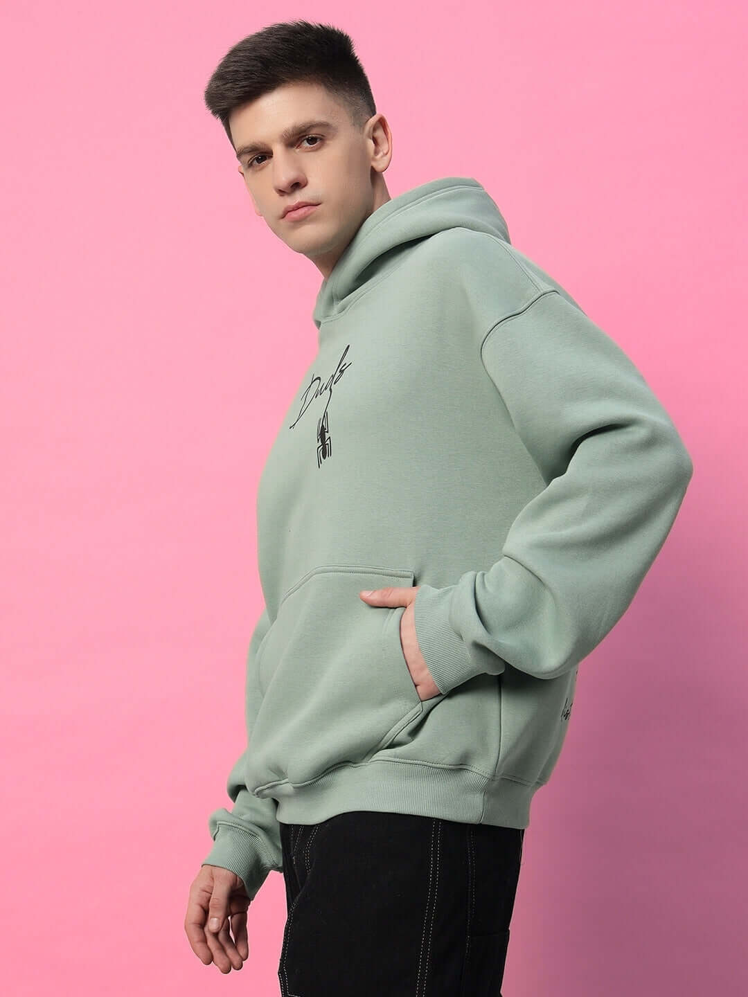 Person wearing Spiderman Oversized Fleece Hoodie Jade Green, showcasing relaxed fit and graphic design against a pink background.